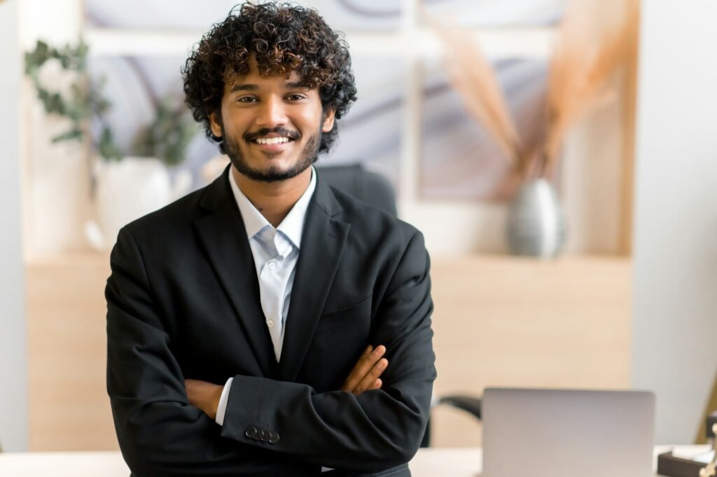 Confident smiling curly Indian business man, small business owner, company leader or sales manager